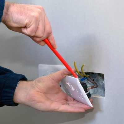 The hands of an electrician installing a power socket